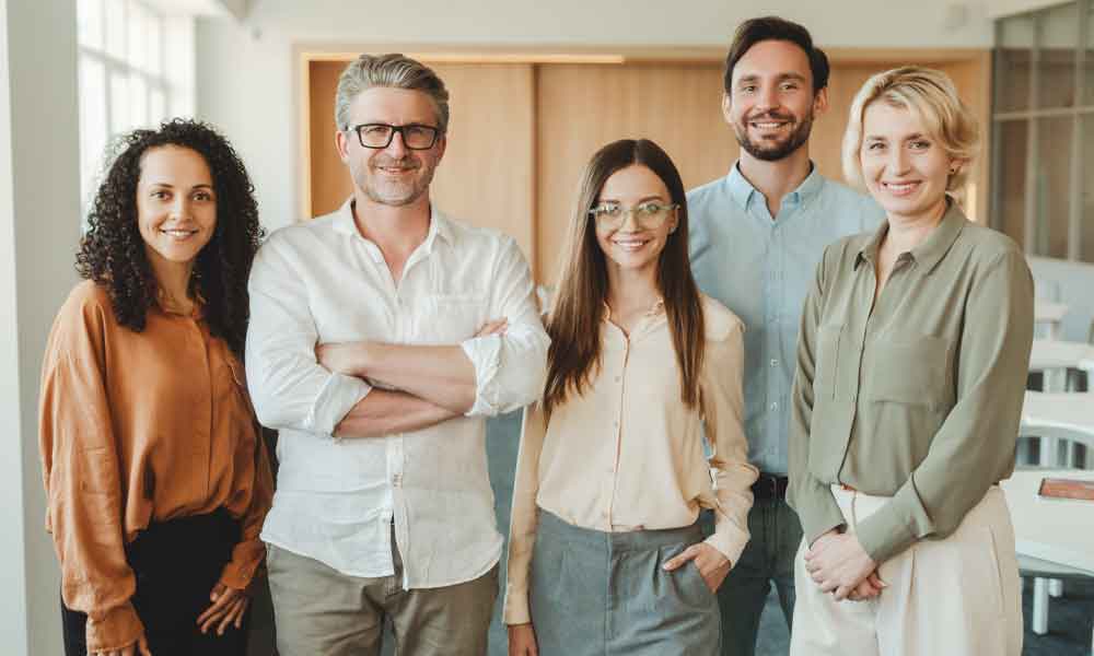 Group of confident, smiling business people, colleagues, managers looking at camera in modern office. Successful business, career concept