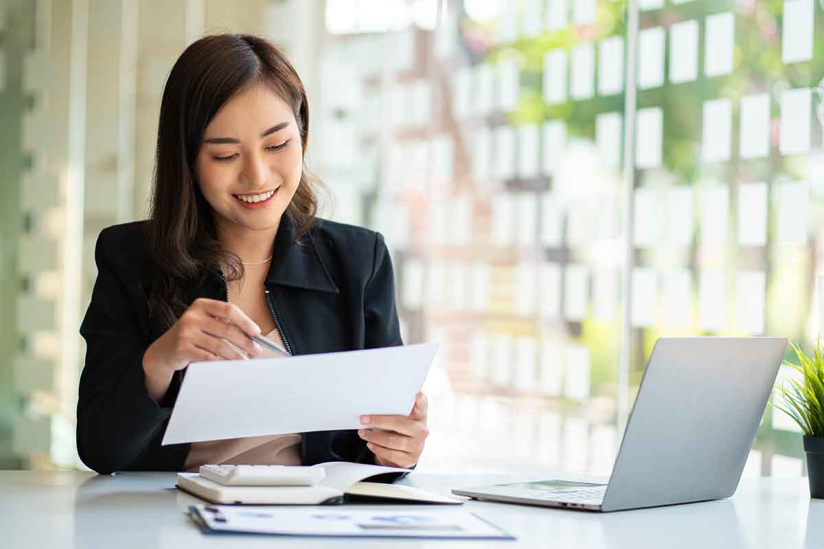 Asian businesswoman working using laptop computer in modern office Make an account analysis report with financial graphs and real estate investment data. financial and tax system concepts