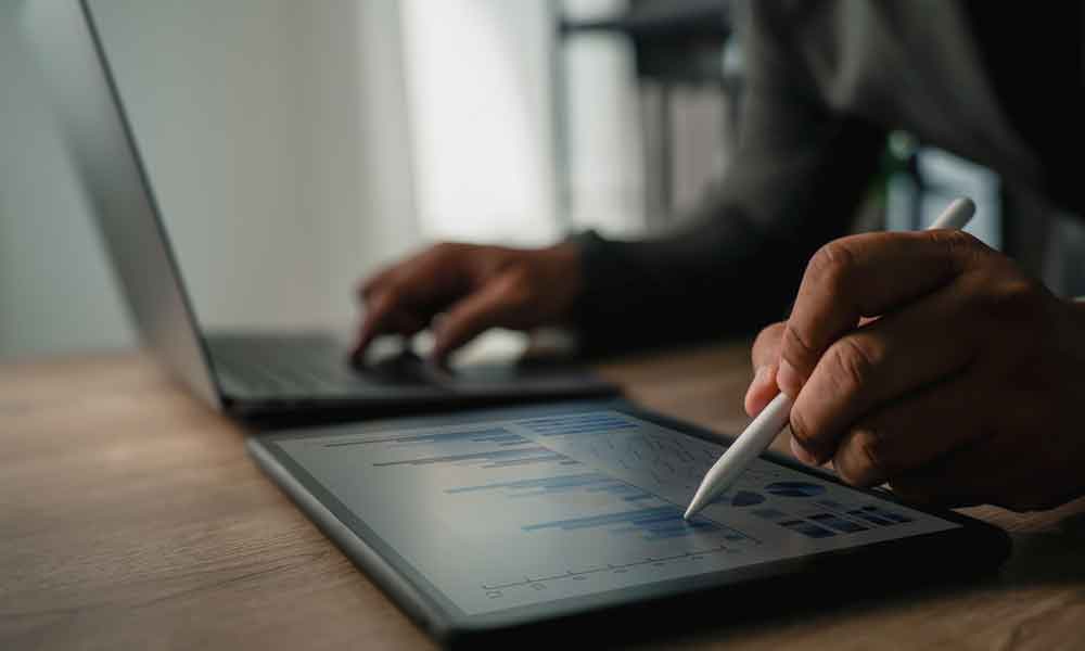 Close up of Accountant in Maple Ridge working on tablet and laptop at a desk.